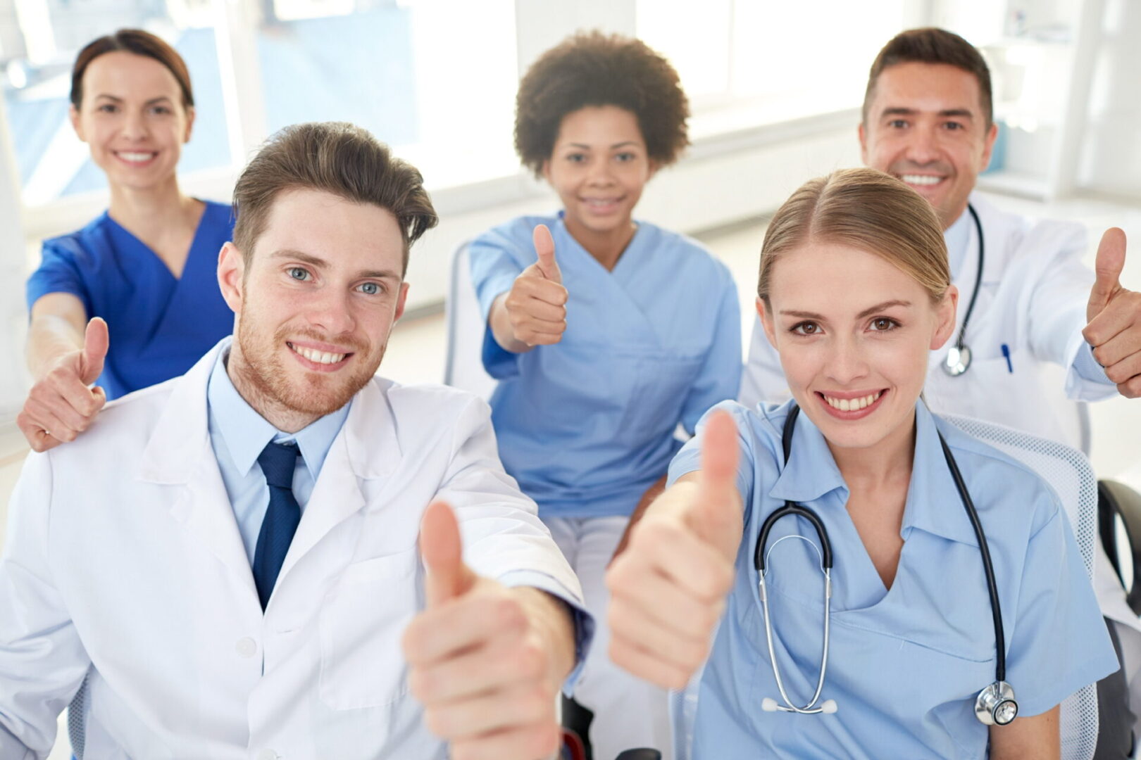 A group of doctors giving thumbs up in an office.
