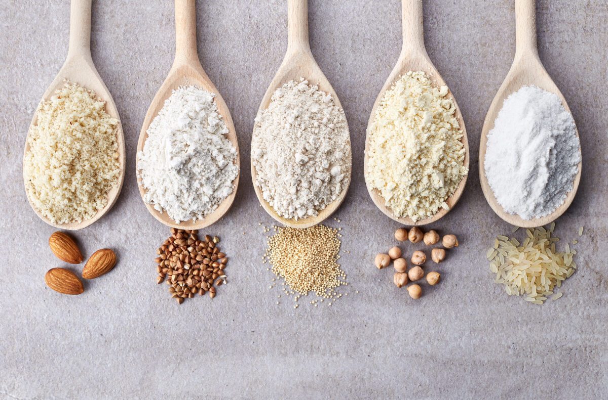 A row of wooden spoons with different types of grains and nuts.